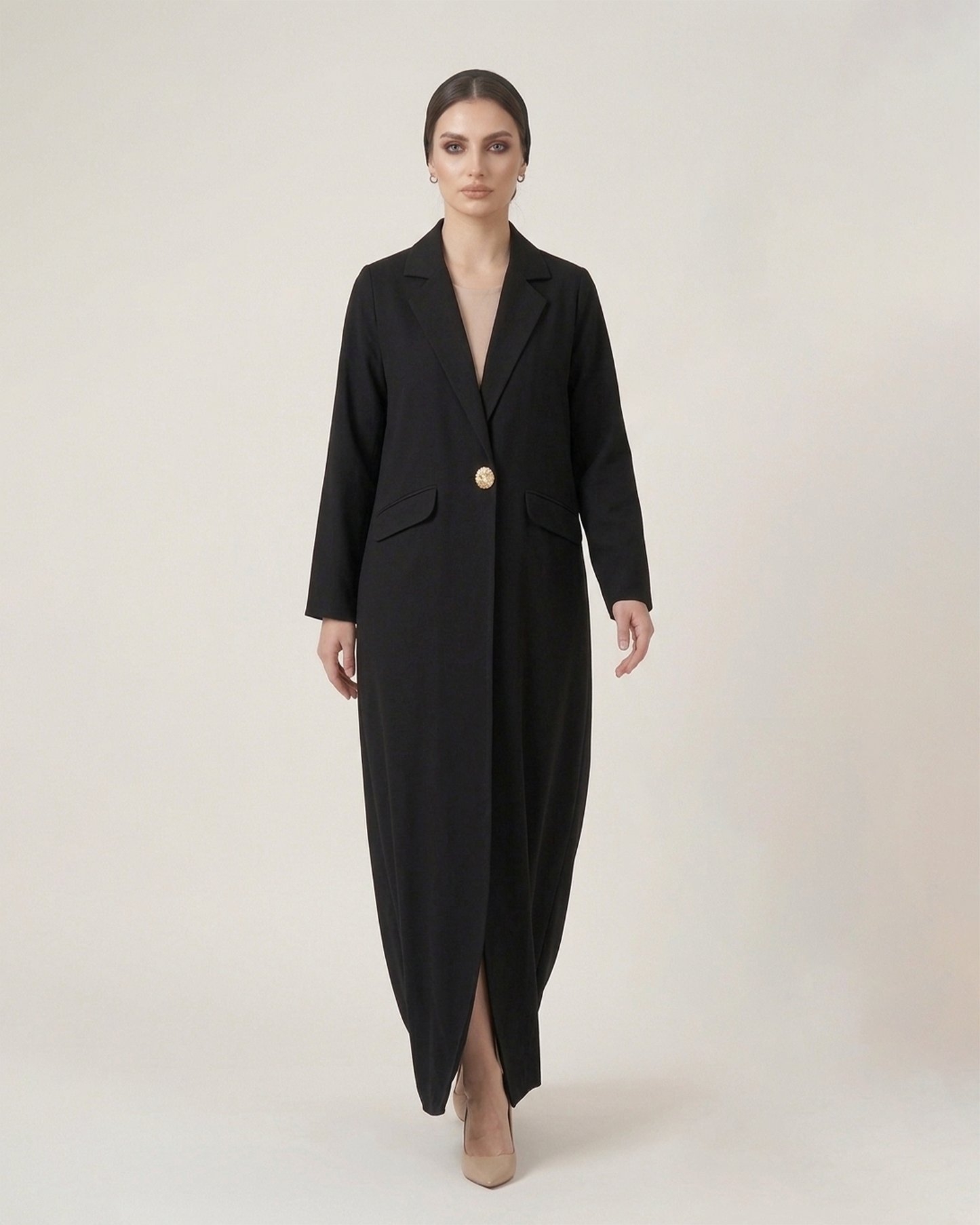 Woman wearing a black coat with a gold button on a white background