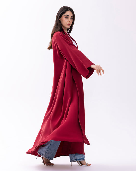 Woman wearing a long red coat over jeans on a white background