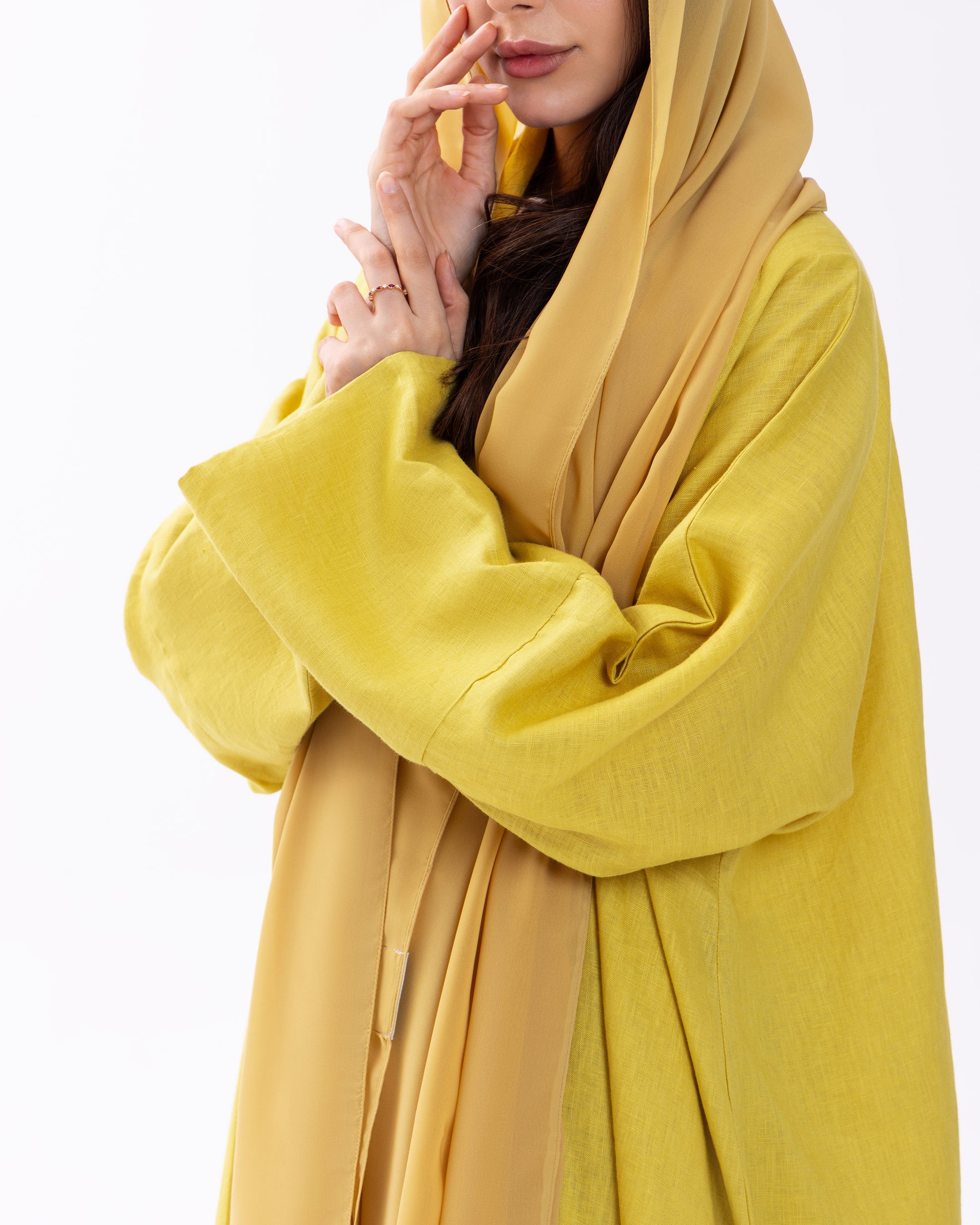 Person wearing a yellow abaya with a matching hijab on a white background