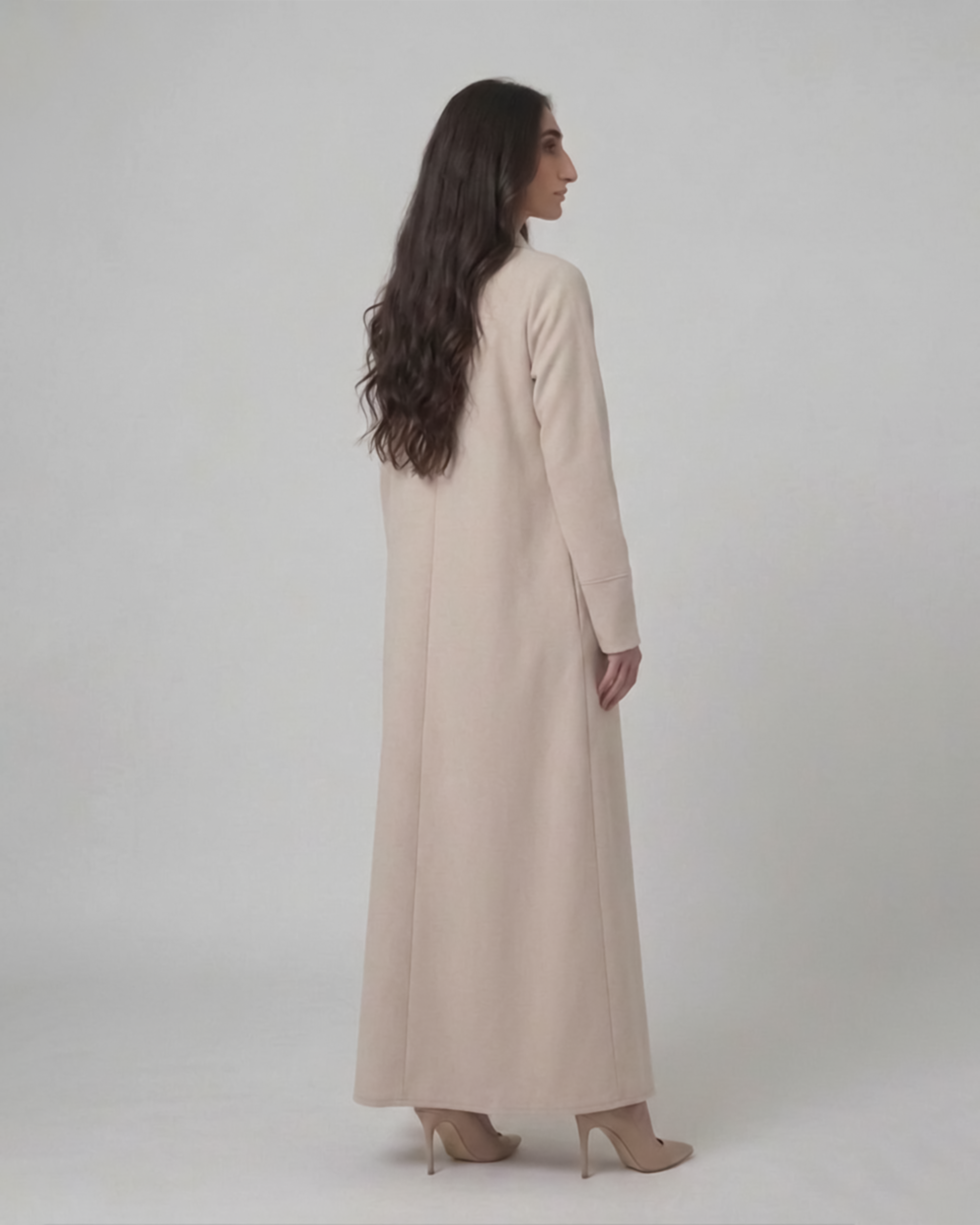 Woman wearing a long beige dress against a white background