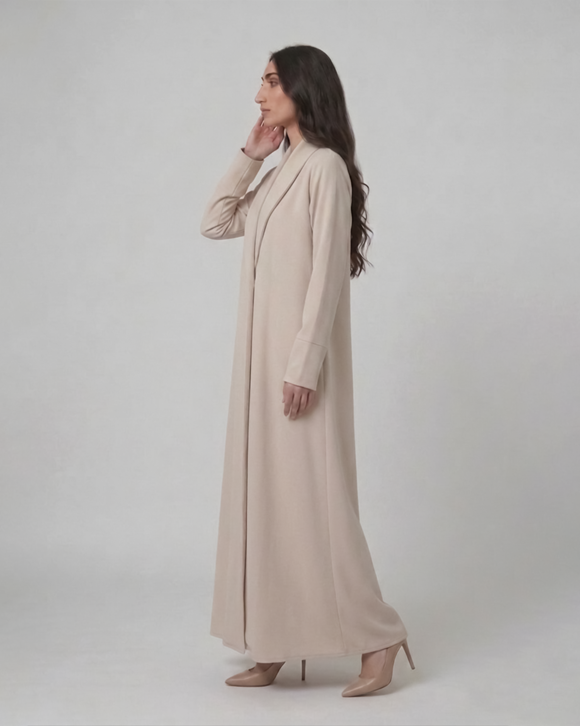 Woman wearing a long beige coat against a white background