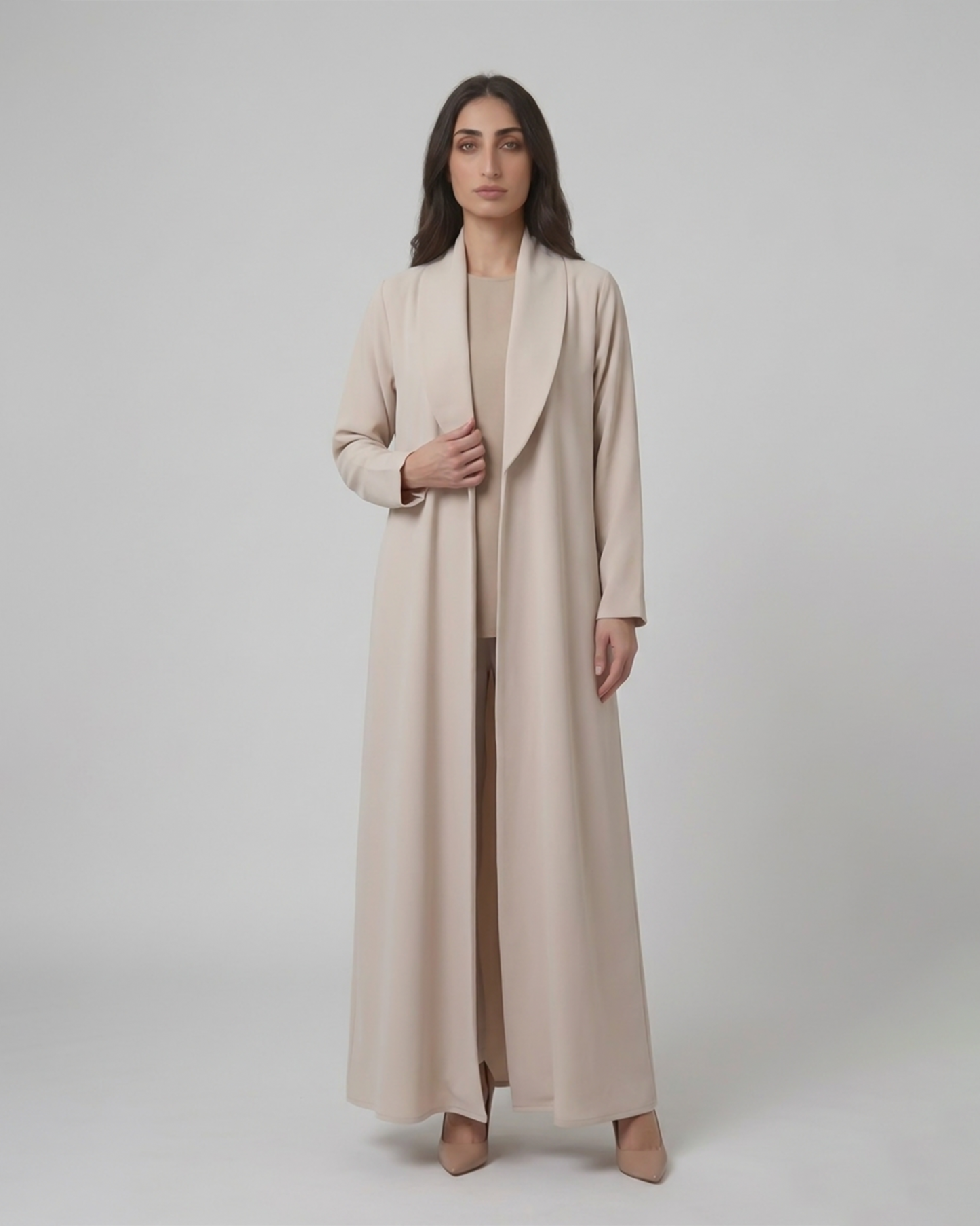 Woman wearing a long beige coat on a plain background