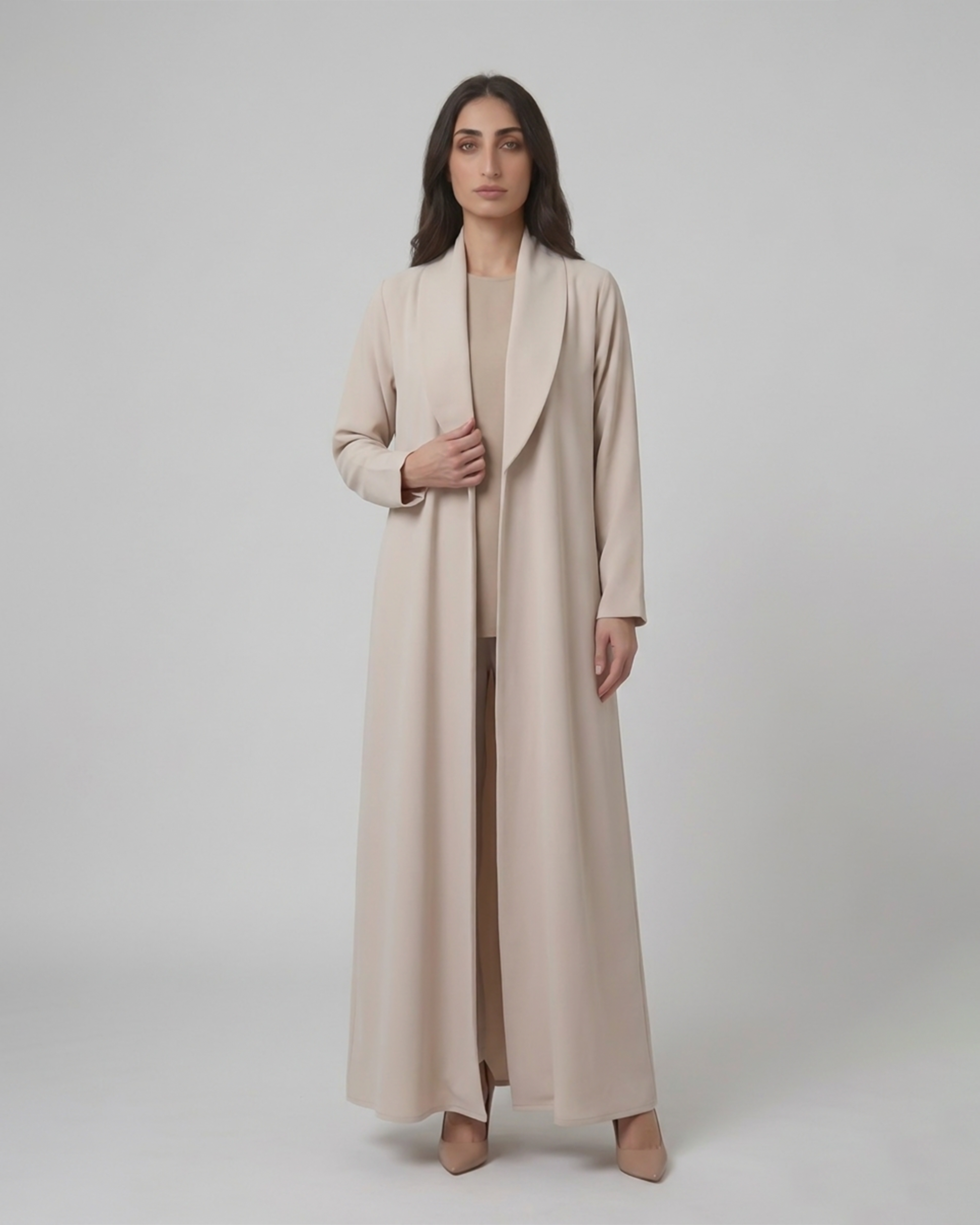 Woman wearing a long beige coat on a plain background