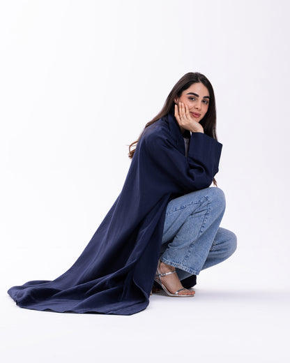 Woman wearing a long navy coat and jeans on a white background