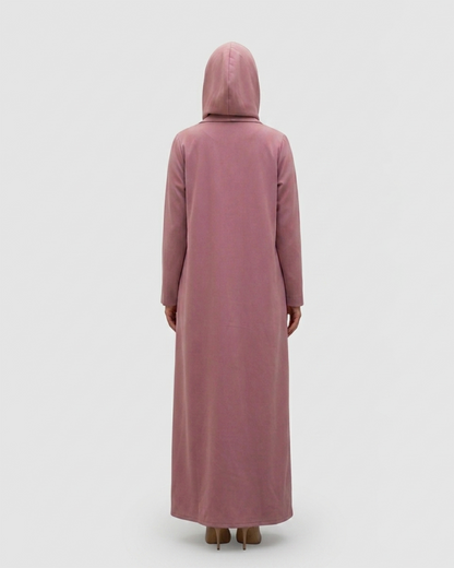Person wearing a long, light pink dress with a hood on a white background