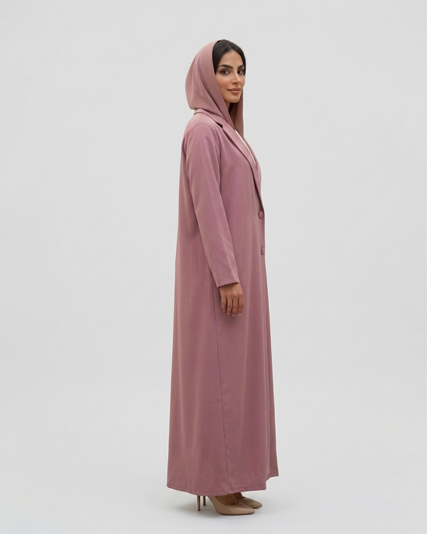 Woman wearing a long pink dress with a hood on a white background
