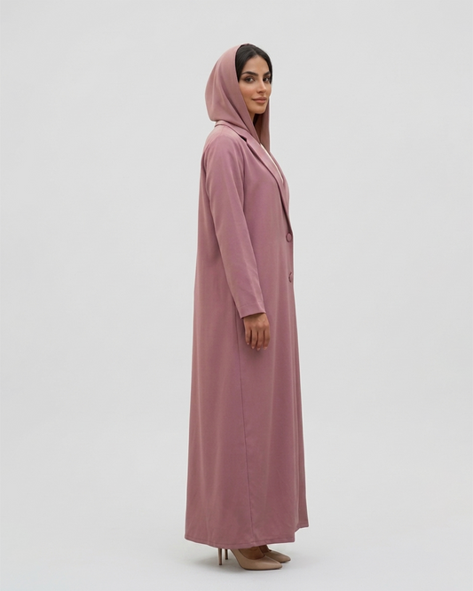 Woman wearing a long pink dress with a hood on a white background