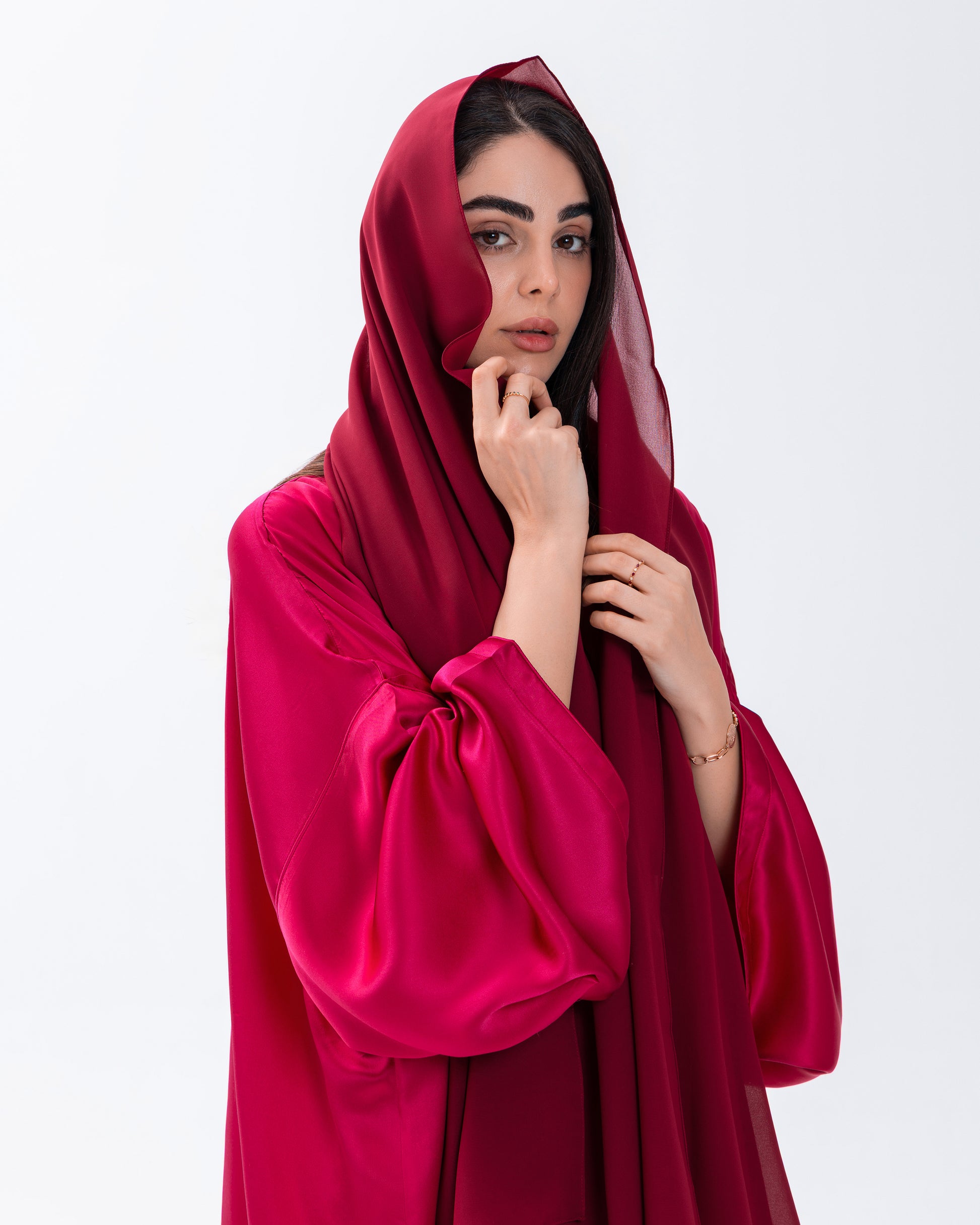 Woman wearing a bright pink hooded garment against a white background
