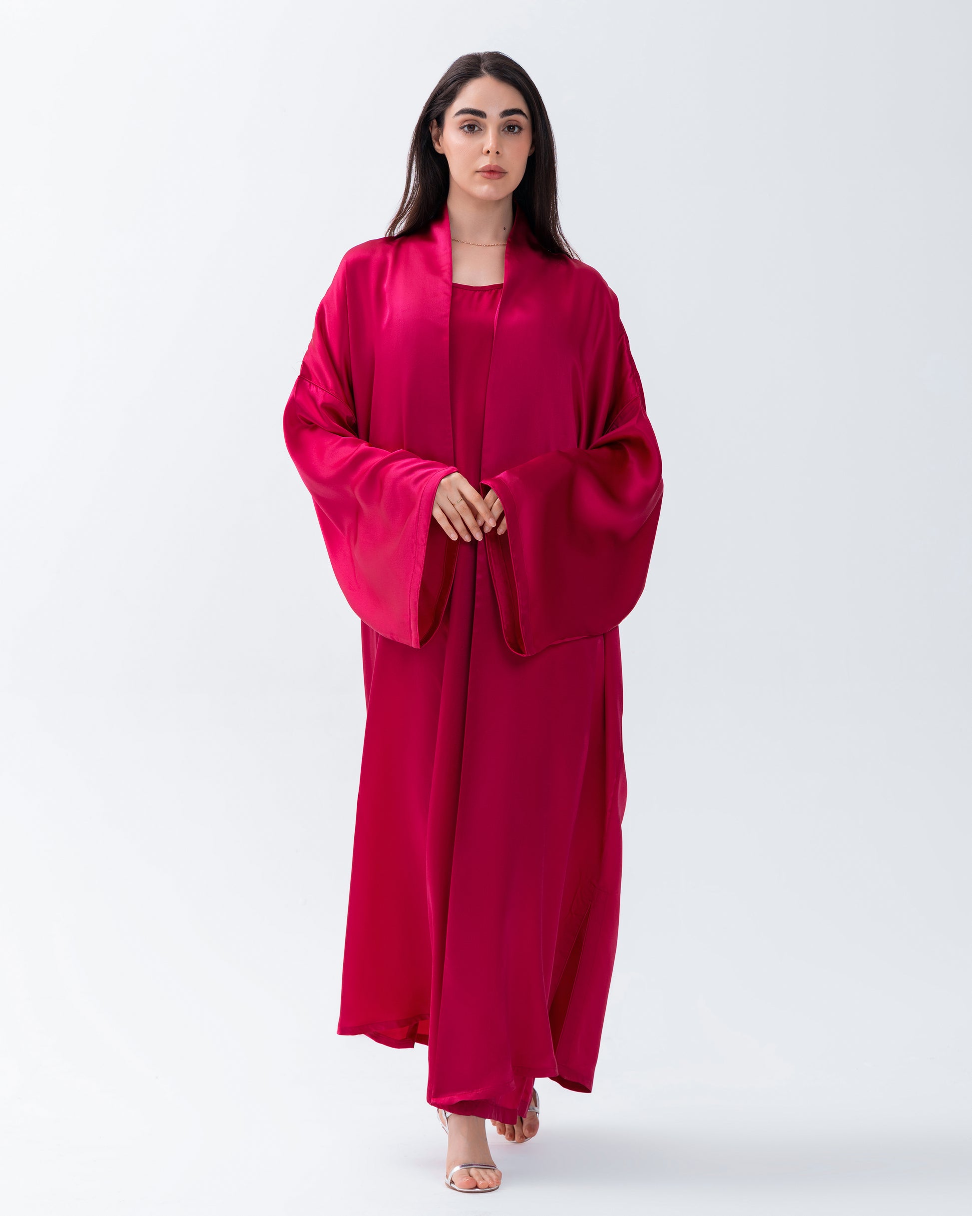 Woman wearing a bright pink abaya on a white background