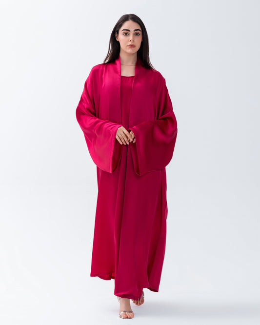 Woman wearing a bright pink abaya on a white background