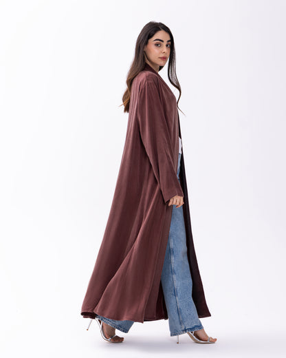 Woman wearing a long brown coat over jeans on a white background