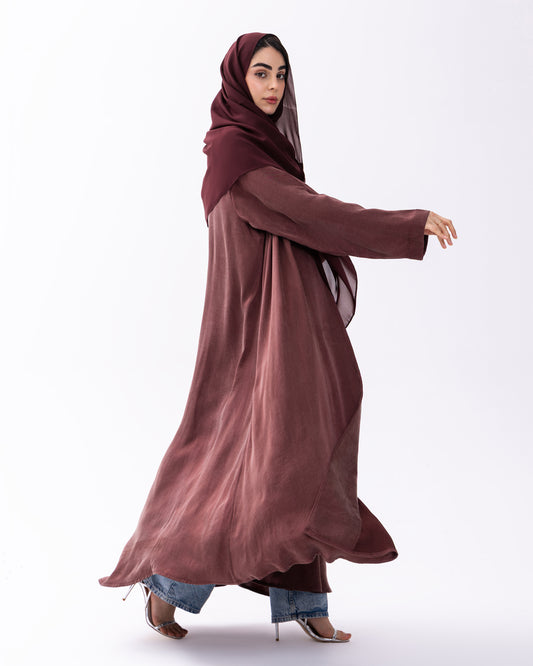 Woman wearing a long burgundy dress with a matching hijab on a white background
