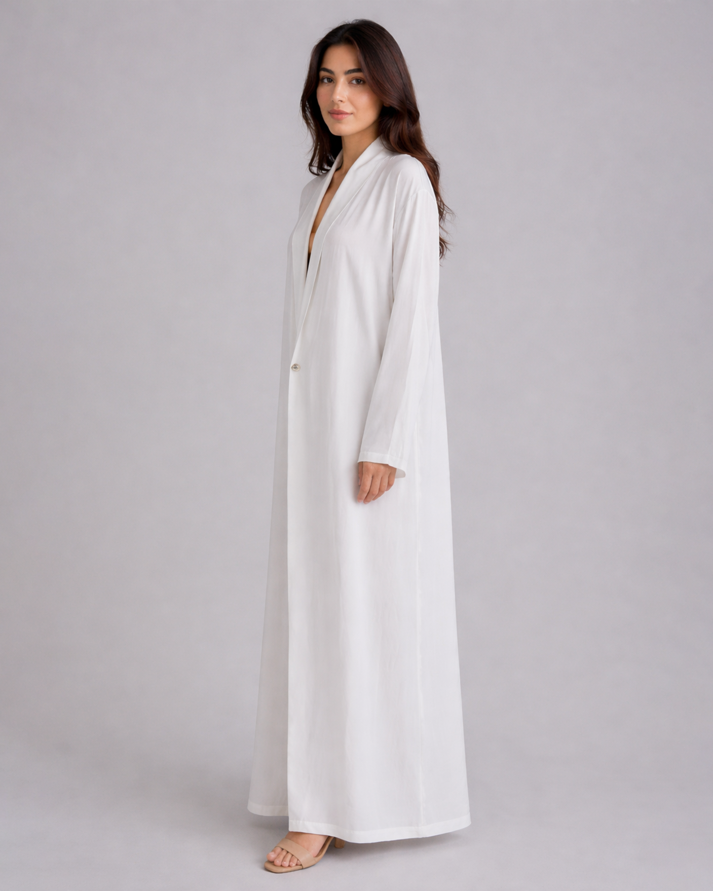 Woman wearing a long white dress against a gray background