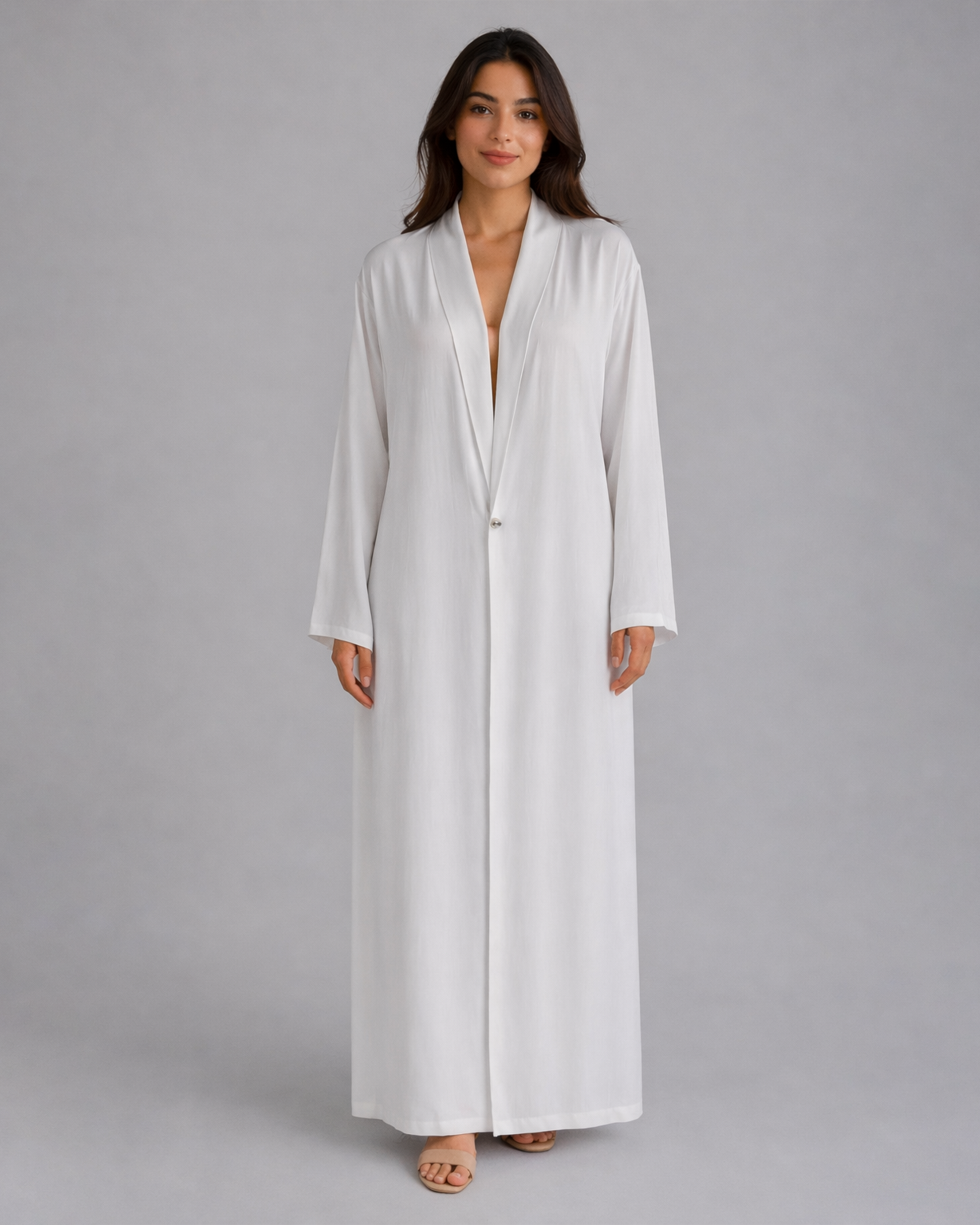 Woman wearing a long white robe against a gray background
