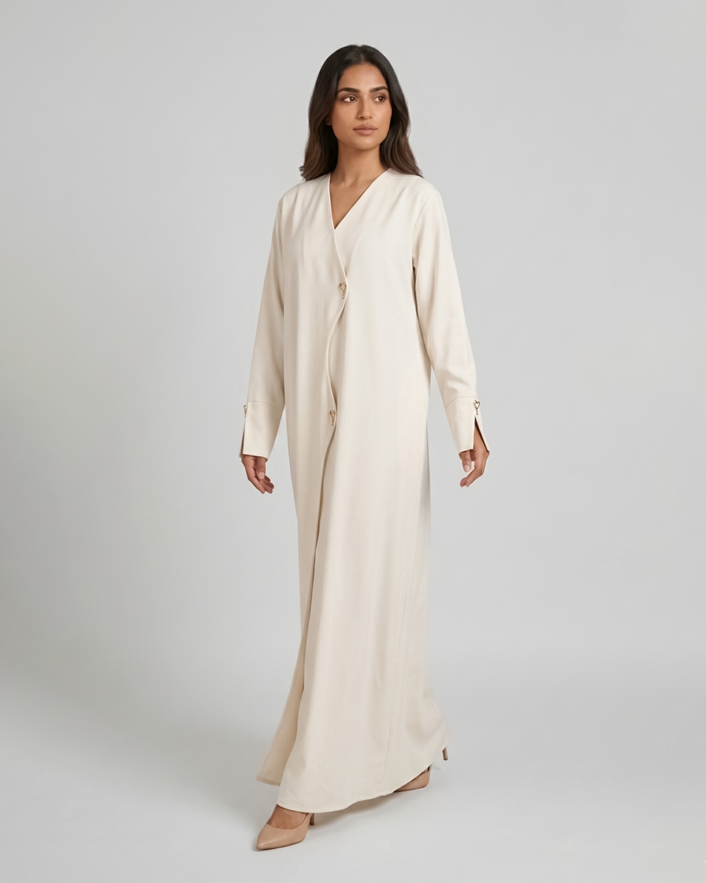Woman wearing a long beige dress against a plain background