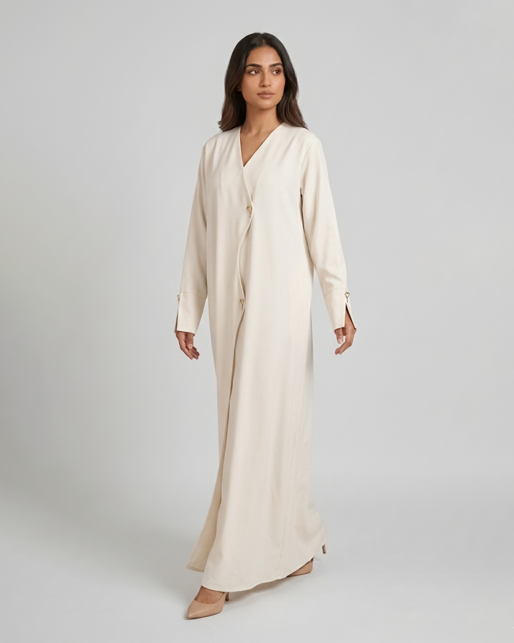 Woman wearing a long beige dress against a plain background