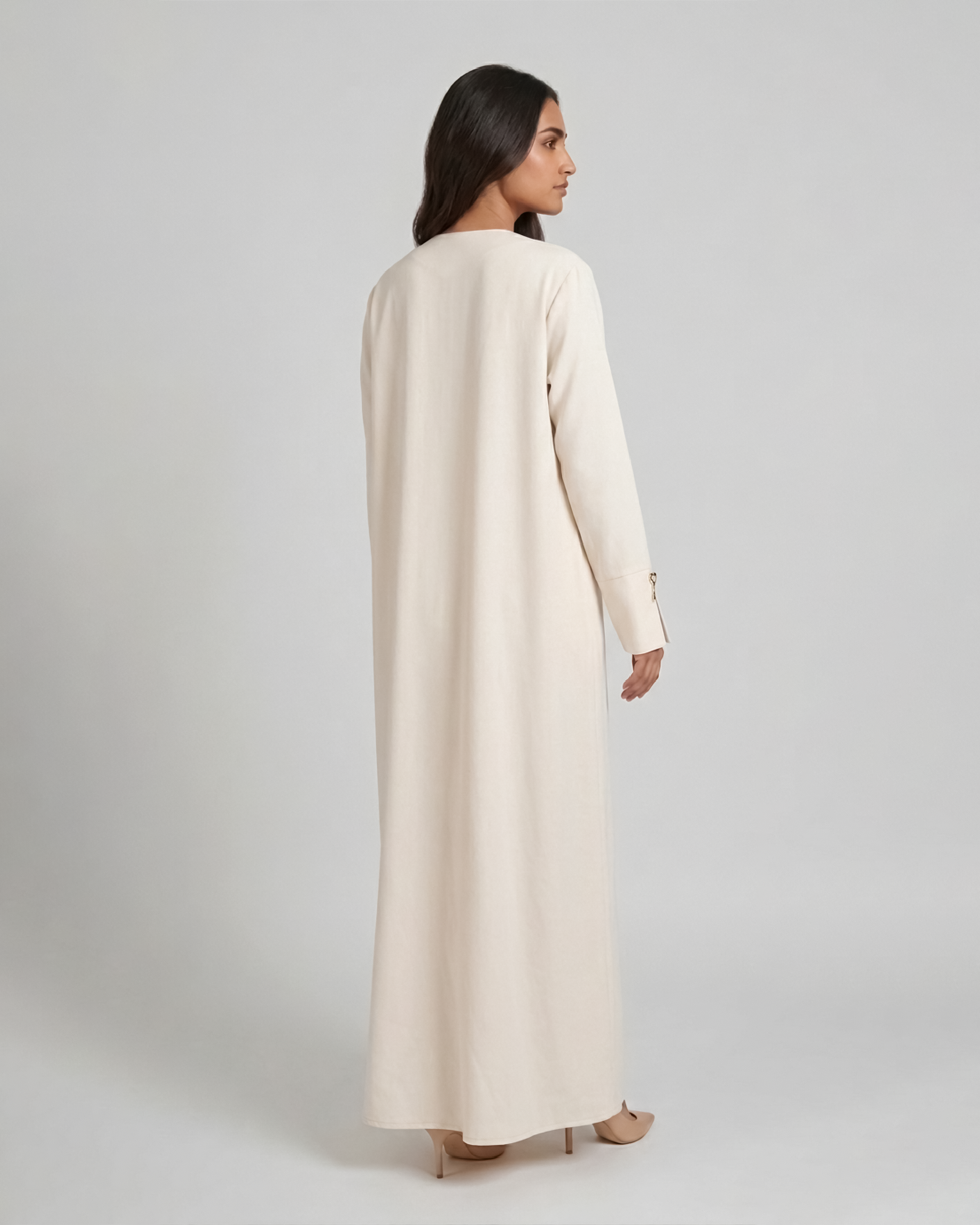 Woman wearing a long beige coat on a plain background