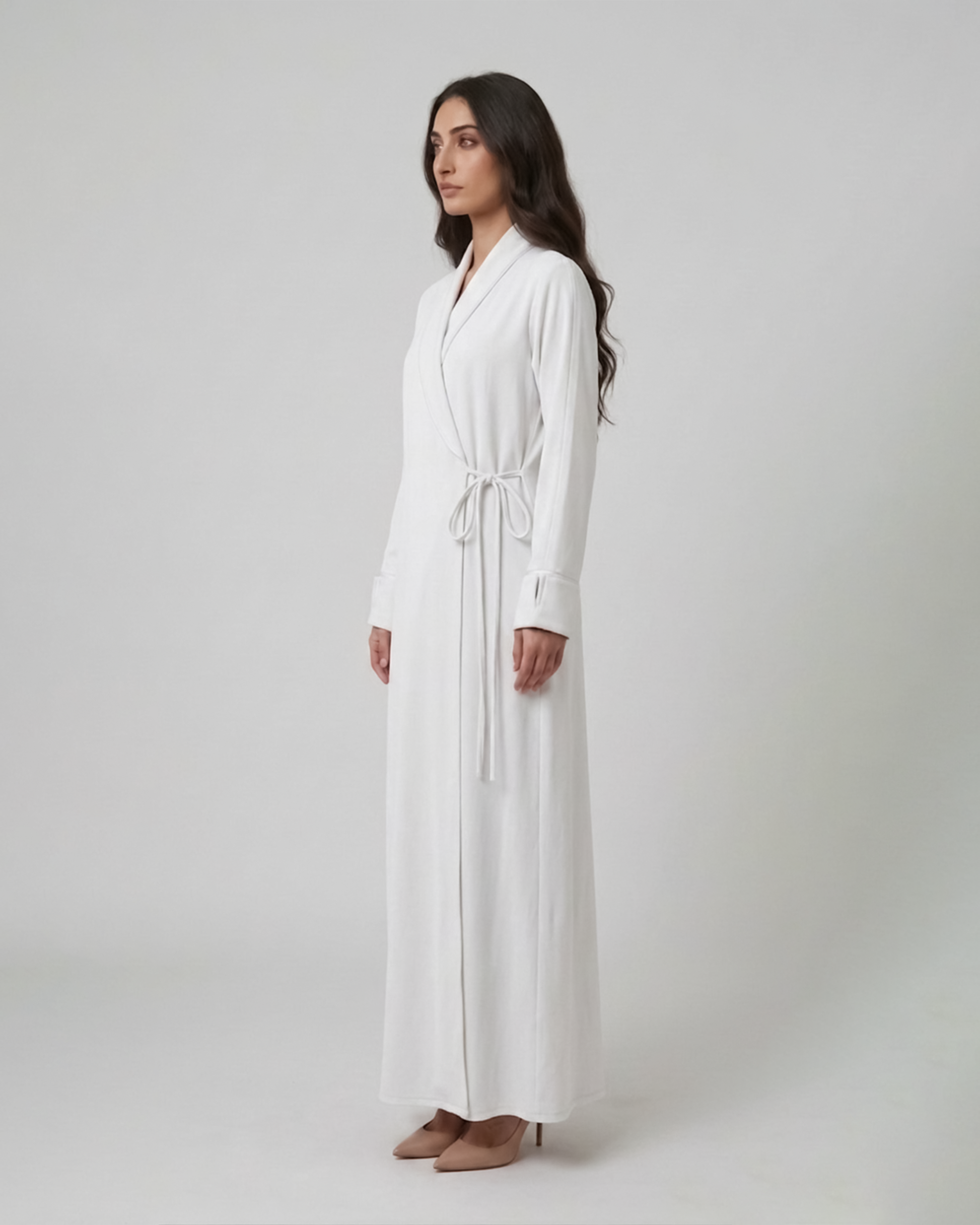Woman wearing a long white dress against a plain background