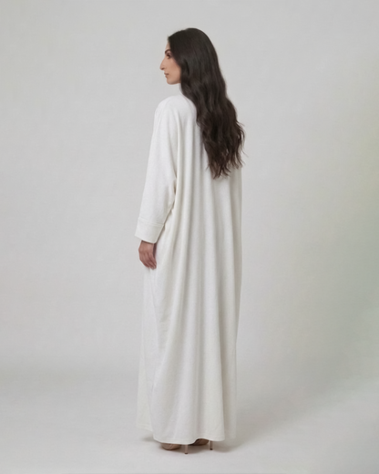 Woman wearing a long white dress against a plain background